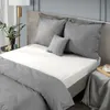 A neatly made bed with grey bedding and white sheets. Produktbild-Vorschau