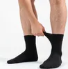 A person's legs and hands are shown, with the person pulling up a black sock. Produktbild-Vorschau