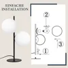 An image showing a modern black table lamp with two white glass globes on the left, and an instructional diagram for its assembly on the right. Náhľad obrázku produktu