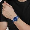 A person's arm wearing a blue leather band watch with a blue dial. Produktbild-Vorschau