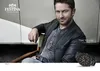 Gerard Butler sitting in a chair, wearing a leather jacket and a watch, with a Festina logo and slogan. Náhled obrázku produktu