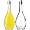 Two glass bottles with cork stoppers, one filled with yellow liquid, the other empty. Voir les images du produit