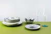 A collection of tableware and glassware arranged on a green surface against a white background. Podgląd zdjęcia produktu