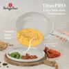 A hand is holding a frying pan with an omelet inside, which is being slid onto a plate with food. Produktbild-Vorschau