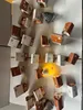 A collection of small, decorative houses and figures arranged on a white surface, with some of the houses illuminated from within. Produktbild-Vorschau