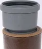 A gray plastic pipe fitting is shown inserted into a brown ceramic pipe. Náhľad obrázku produktu