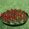 A circular flower bed with red flowers and some white flowers, bordered by a black metal edging, set in a grassy lawn. Produktbild-Vorschau