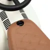 A close-up view of a baby ride-on toy's seat and steering wheel. Produktbild-Vorschau
