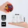 A hand holding a lid with fruit pattern, and a hand holding a glass jar with dimensions indicated. Produktbild-Vorschau