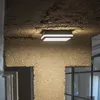 A close-up shot of a modern, square LED ceiling light mounted on a rough concrete ceiling. Náhľad obrázku produktu