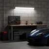 A garage or workshop setting with a workbench, tools, storage bins, and a blue car. Produktbild-Vorschau