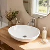 A bathroom sink on a wooden countertop with a mirror and some decorative items. Produktbild-Vorschau