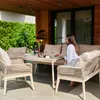 A woman is sitting at a table on a patio, eating a meal. The patio is furnished with a table and chairs, and surrounded by greenery. Náhľad obrázku produktu