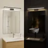 A split image showing a modern bathroom vanity with a mirror and light fixture in both a bright and dim setting. Náhled obrázku produktu