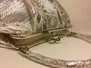 A close-up of a silver handbag with a clasp closure. Podgląd zdjęcia produktu