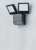 A black and gray LED floodlight with an integrated motion detector is mounted on a light gray wall. Podgląd zdjęcia produktu