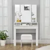 A white vanity table with a tri-fold mirror, a lamp, and beauty products, with a white stool in front. Náhľad obrázku produktu