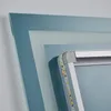 A close-up view of the corner of an LED bathroom mirror, showing the integrated LED strip and the frame. Podgląd zdjęcia produktu