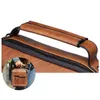 A close-up of a brown leather bag handle and zipper, with a small inset image of a person holding the bag. Produktbild-Vorschau