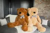 Two large teddy bears sitting on a sofa with pillows and a blanket. Podgląd zdjęcia produktu