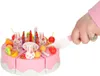 A hand is cutting a toy birthday cake with a plastic knife. Podgląd zdjęcia produktu