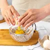 A person is separating an egg yolk from the white using a kitchen tool. Produktbild-Vorschau