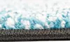 A close-up view of the edge of a rug, showing the texture of the fibers and the backing. Náhled obrázku produktu