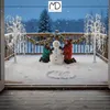 Two children building a snowman on a snowy deck at dusk, with decorative trees and lights. Podgląd zdjęcia produktu