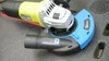 An angle grinder with a dust extraction cover attached, resting on a dark surface. Náhled obrázku produktu