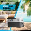 A portable cooler box is placed on a beach with a couch and palm trees in the background. Produktbild-Vorschau