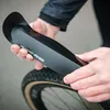 A person is holding a black bicycle fender over a bicycle tire. Produktbild-Vorschau