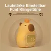 A cute, yellow, capybara-shaped alarm clock with a digital display and a small orange ball on its head, set against a gradient background. Produktbild-Vorschau