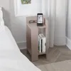 A modern nightstand with books and a phone docked on top, placed next to a bed.