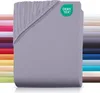 A folded jersey fitted sheet is shown, with a stack of other colored sheets visible in the background. Produktbild-Vorschau