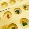 A close-up view of a wooden board game with several small, colorful stones in individual carved-out spaces. Produktbild-Vorschau