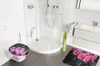 A modern bathroom with a toilet, shower, and vanity, decorated with orchid-themed accessories. Produktbild-Vorschau