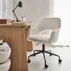 A white bouclé office chair with black wheels is placed next to a wooden desk. Anteprima dell’immagine prodotto