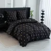 A neatly made bed with black bedding featuring a gold heart pattern. Produktbild-Vorschau