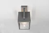 A modern, gray outdoor wall lamp with a clear glass shade is mounted on a white wall. Anteprima dell’immagine prodotto