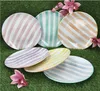 A collection of six striped plates arranged on a green grassy surface, with pink flowers as decoration. Voir les images du produit