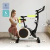 A woman is demonstrating the adjustable features of a stationary exercise bike, with various dimensions and weight limits indicated by text overlays. Produktbild-Vorschau