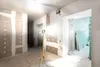 Interior of a room under construction, with a bright LED work light on a tripod illuminating the space. Drywall is installed and taped, and materials like drywall sheets are visible in the background. Anteprima dell’immagine prodotto