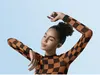 A young woman with her eyes closed and arms raised, wearing earbuds, against a light blue background. Produktbild-Vorschau