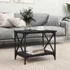 A black side table with a shelf is placed in a living room setting next to a gray sofa. Podgląd zdjęcia produktu
