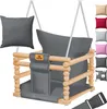 A KIDIZ baby swing with a wooden frame and gray fabric seat, shown with an additional gray cushion and a selection of colored cushions on the right side. Produktbild-Vorschau