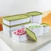 A collection of white plastic freezer containers with green lids, some filled with frozen raspberries and peas, arranged on a countertop. Produktbild-Vorschau
