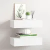 Two white floating shelves mounted on a white wall, decorated with a framed print of a plant, a small cactus in a pot, a reed diffuser, and two books with a white decorative vase on top. Produktbild-Vorschau
