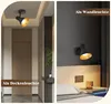 A split image showing a black spotlight fixture used as a ceiling light in a hallway and as a wall light next to a bed. Náhľad obrázku produktu