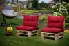 Two red pallet chairs with cushions are placed on a green lawn in a garden setting. A hanging chair and a basket of bananas are also visible. Produktbild-Vorschau