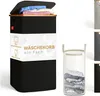 A black laundry basket with a wooden lid and a label showing product information, placed on a white background. Other laundry baskets in different colors are shown on the right side. Produktbild-Vorschau